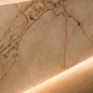 Face de pedra branca quente com veios finos sobre uma linha suave de luz